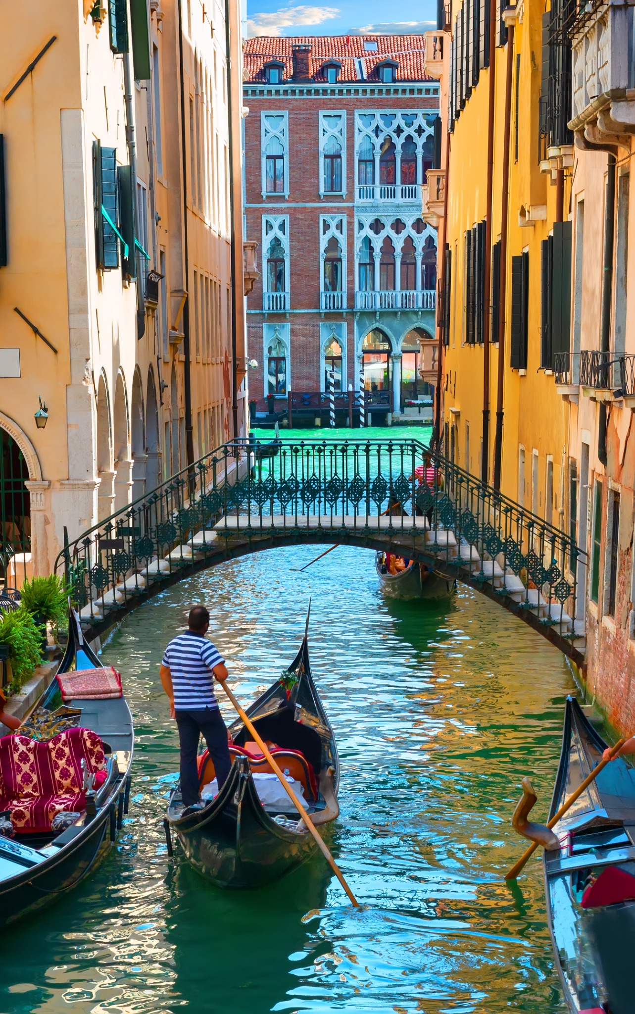 Gôndolas em um canal de Veneza, entre fachadas e uma ponte